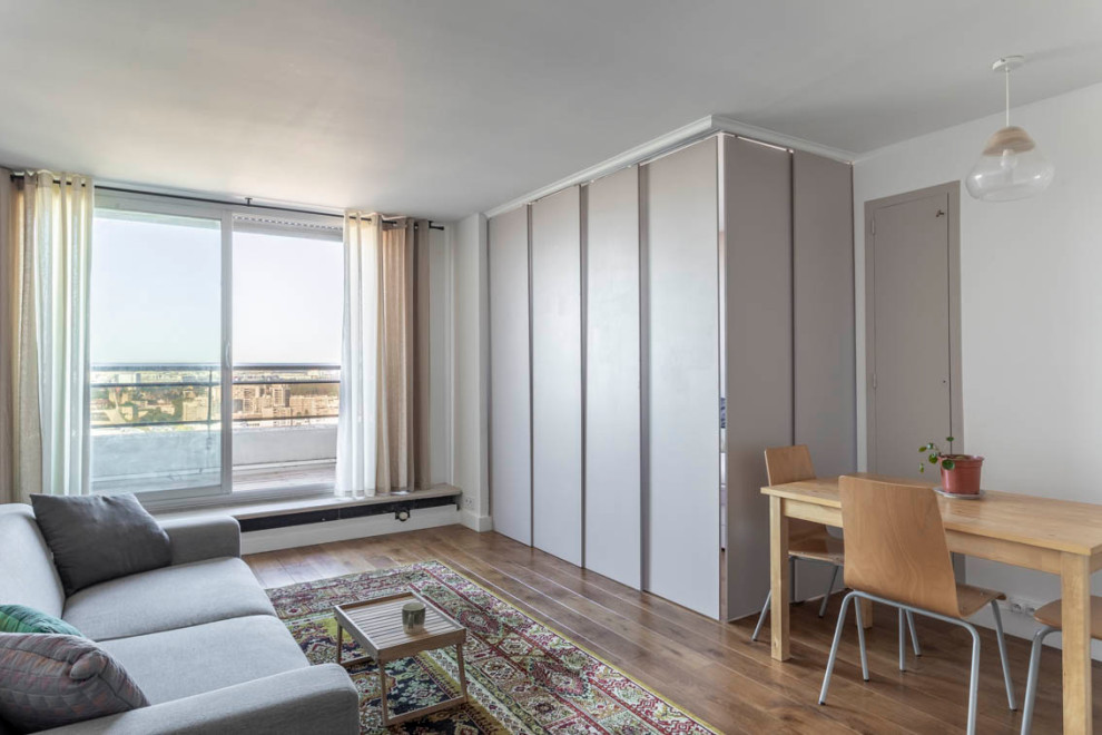 Aménagement d'une salle de séjour contemporaine de taille moyenne et ouverte avec un mur blanc, un sol en bois brun et un sol marron.