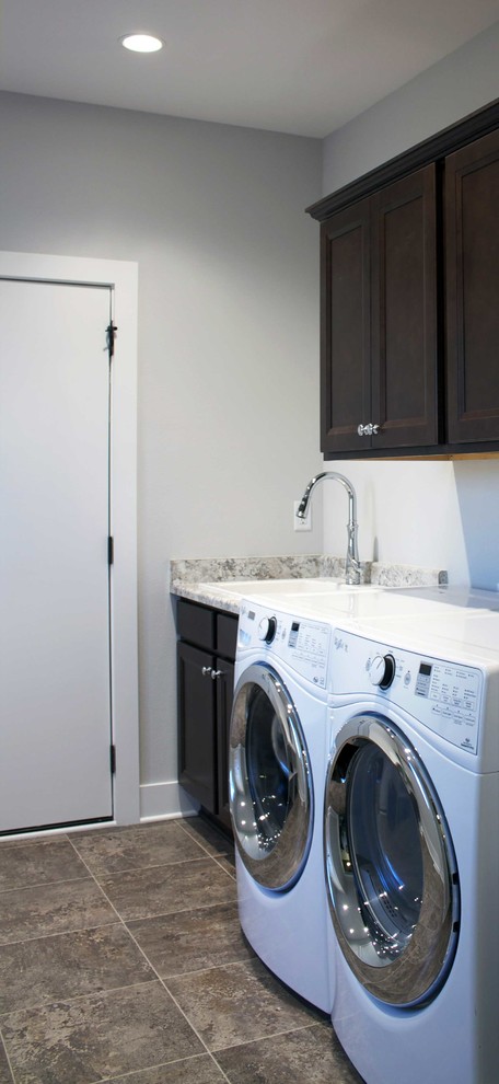 Mid-sized country single-wall dedicated laundry room in Other with a farmhouse sink, grey walls, ceramic floors, a side-by-side washer and dryer, dark wood cabinets, beaded inset cabinets and granite benchtops.