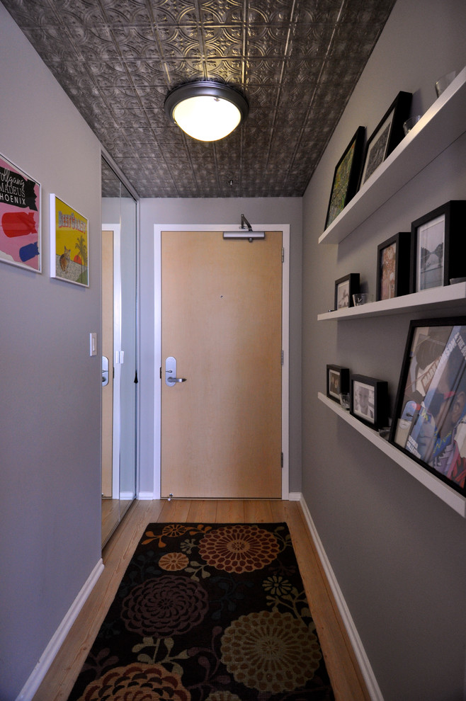 This is an example of a small transitional hallway in Los Angeles with grey walls and light hardwood floors.