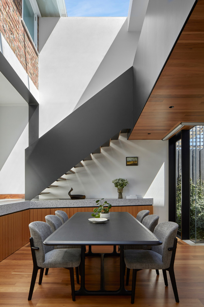 Idée de décoration pour une salle à manger ouverte sur le salon design de taille moyenne avec un mur blanc, un sol en bois brun et un plafond en lambris de bois.