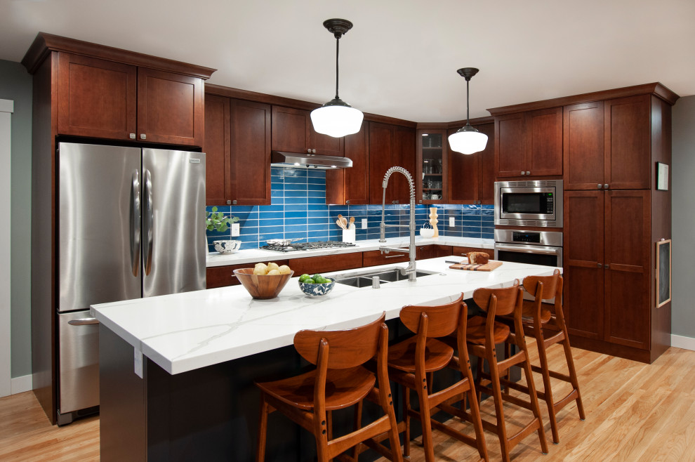 Eat-in kitchen - large transitional l-shaped light wood floor and yellow floor eat-in kitchen idea in San Francisco with a double-bowl sink, shaker cabinets, brown cabinets, blue backsplash, glass tile backsplash, stainless steel appliances, an island and white countertops