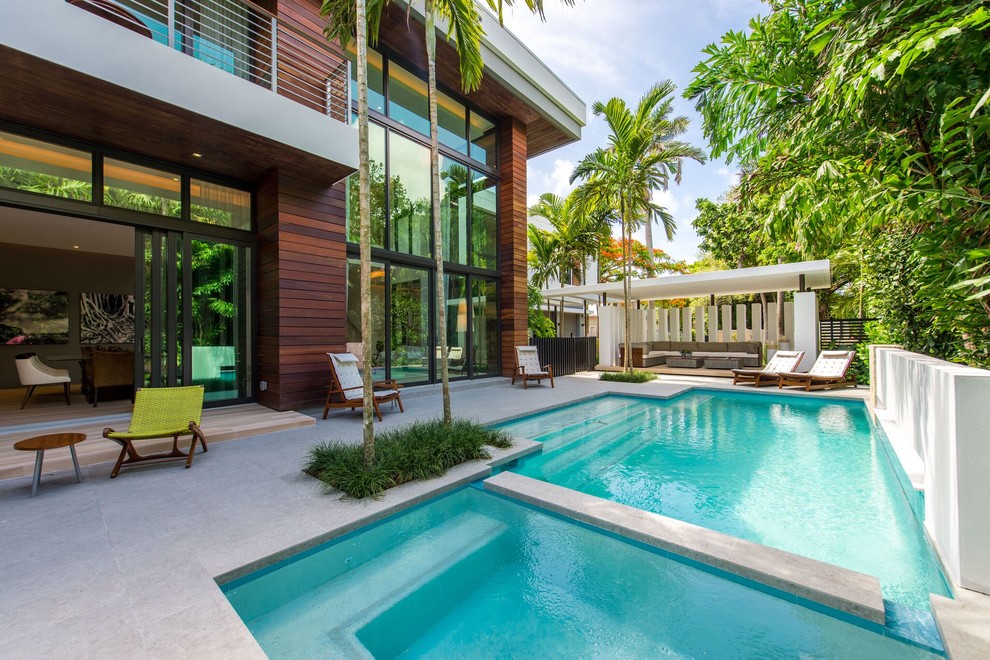 Large tropical backyard custom-shaped lap pool in Miami with a hot tub.
