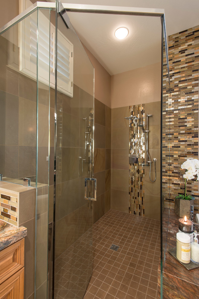 Design ideas for a large contemporary master bathroom in Phoenix with an undermount sink, raised-panel cabinets, medium wood cabinets, granite benchtops, a drop-in tub, a curbless shower, a two-piece toilet, brown tile, glass tile, beige walls and limestone floors.