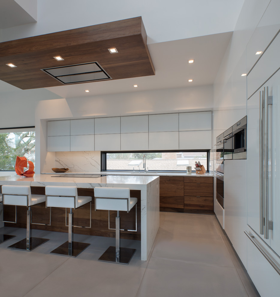 Photo of a large modern l-shaped open plan kitchen in Baltimore with flat-panel cabinets, white cabinets, marble benchtops, white splashback, stone slab splashback, stainless steel appliances, concrete floors, with island, grey floor and white benchtop.