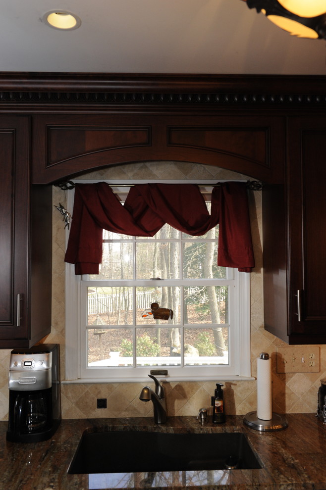 Mid-sized transitional u-shaped limestone floor enclosed kitchen photo in Baltimore with an undermount sink, beaded inset cabinets, dark wood cabinets, granite countertops, beige backsplash, stone tile backsplash, stainless steel appliances and a peninsula