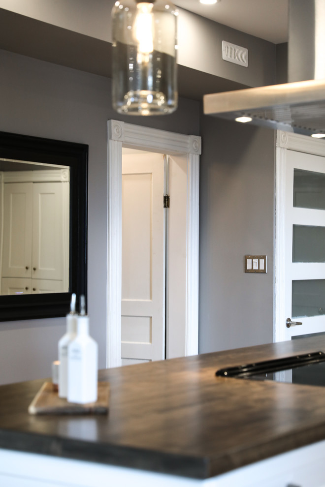 Inspiration for a mid-sized transitional single-wall medium tone wood floor and brown floor eat-in kitchen remodel with a farmhouse sink, shaker cabinets, white cabinets, white backsplash, stainless steel appliances, an island and white countertops