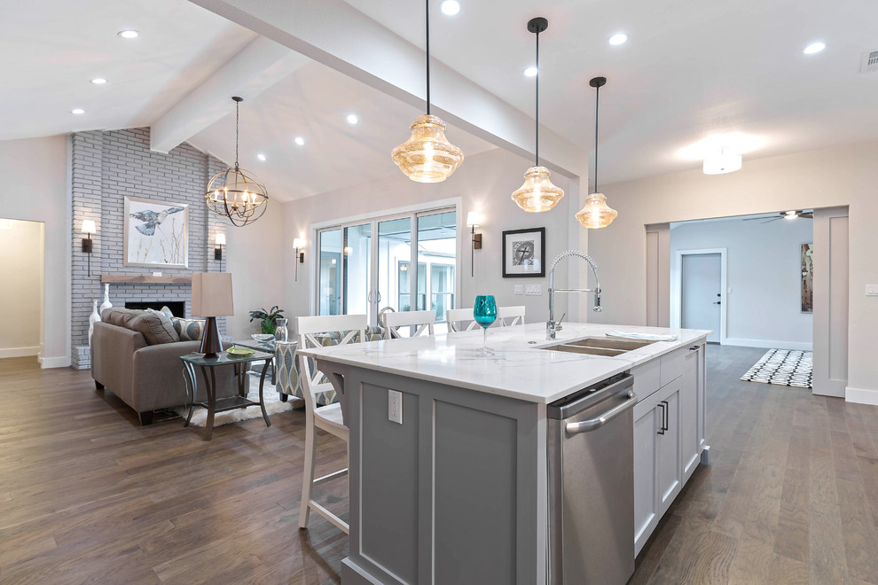 Open concept kitchen - mid-sized transitional galley medium tone wood floor open concept kitchen idea in Dallas with a double-bowl sink, shaker cabinets, gray cabinets, quartz countertops, white backsplash, subway tile backsplash, stainless steel appliances and an island