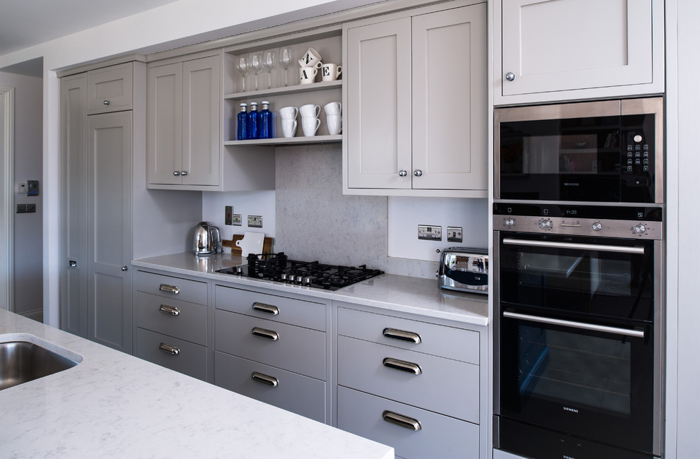 Inspiration for a large traditional galley open plan kitchen in Dublin with an integrated sink, recessed-panel cabinets, grey cabinets, quartz benchtops, grey splashback, porcelain floors and with island.