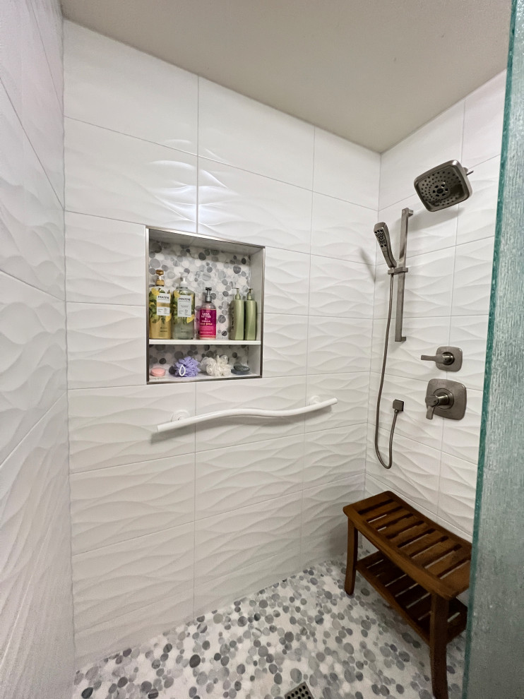 Exemple d'une douche en alcôve principale chic de taille moyenne avec un carrelage blanc, des carreaux de céramique, un sol en galet, un sol multicolore, une cabine de douche à porte battante et une niche.