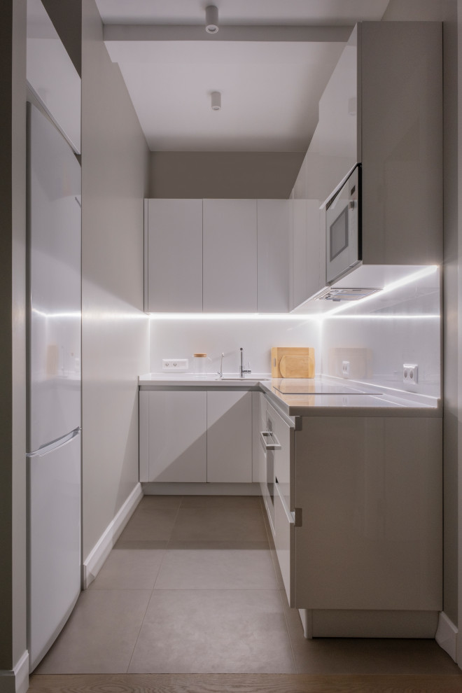 Photo of a small l-shaped separate kitchen in Moscow with an undermount sink, flat-panel cabinets, white cabinets, solid surface benchtops, white splashback, white appliances, porcelain floors, no island, beige floor and white benchtop.