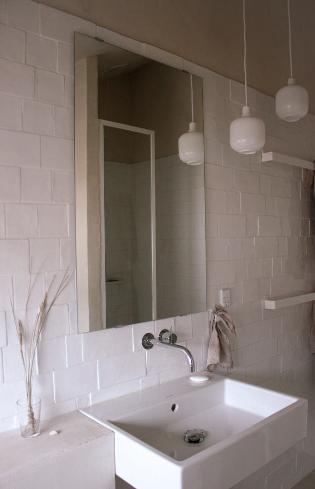 Photo of a scandi shower room bathroom in Hamburg with white cabinets, an alcove shower, a wall mounted toilet, white tiles, ceramic tiles, beige walls, a wall-mounted sink, beige floors, a wall niche and a single sink.