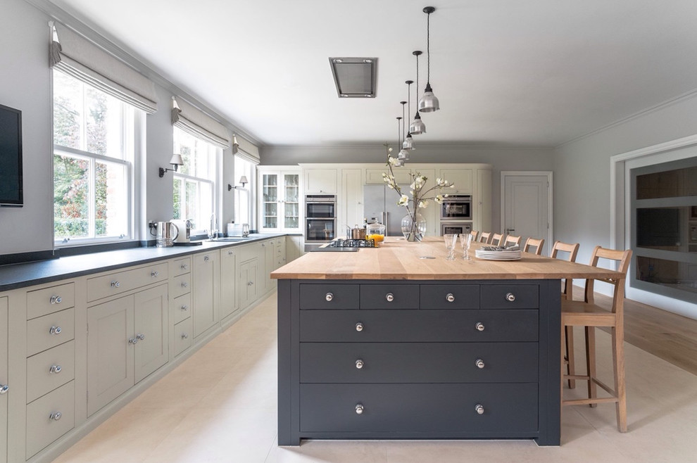 Inspiration for an expansive country l-shaped eat-in kitchen in Berlin with shaker cabinets, grey cabinets, wood benchtops, with island, a double-bowl sink and stainless steel appliances.