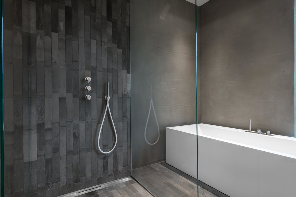 Imagen de cuarto de baño moderno con bañera exenta, ducha a ras de suelo, baldosas y/o azulejos grises, paredes grises, suelo gris y ducha abierta