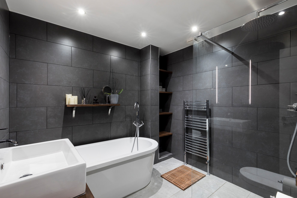 Design ideas for a large modern bathroom in London with raised-panel cabinets, dark wood cabinets, a freestanding tub, a shower/bathtub combo, a one-piece toilet, gray tile, cement tile, grey walls, ceramic floors, a pedestal sink, wood benchtops and brown benchtops.