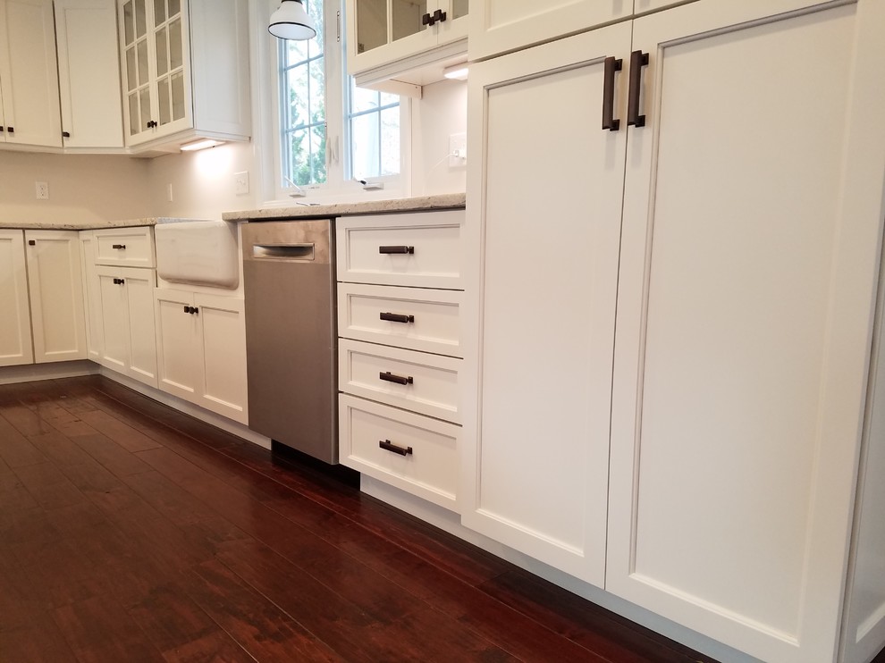 Eat-in kitchen - mid-sized transitional l-shaped dark wood floor and brown floor eat-in kitchen idea with a farmhouse sink, shaker cabinets, white cabinets, granite countertops, white backsplash, subway tile backsplash, stainless steel appliances and an island