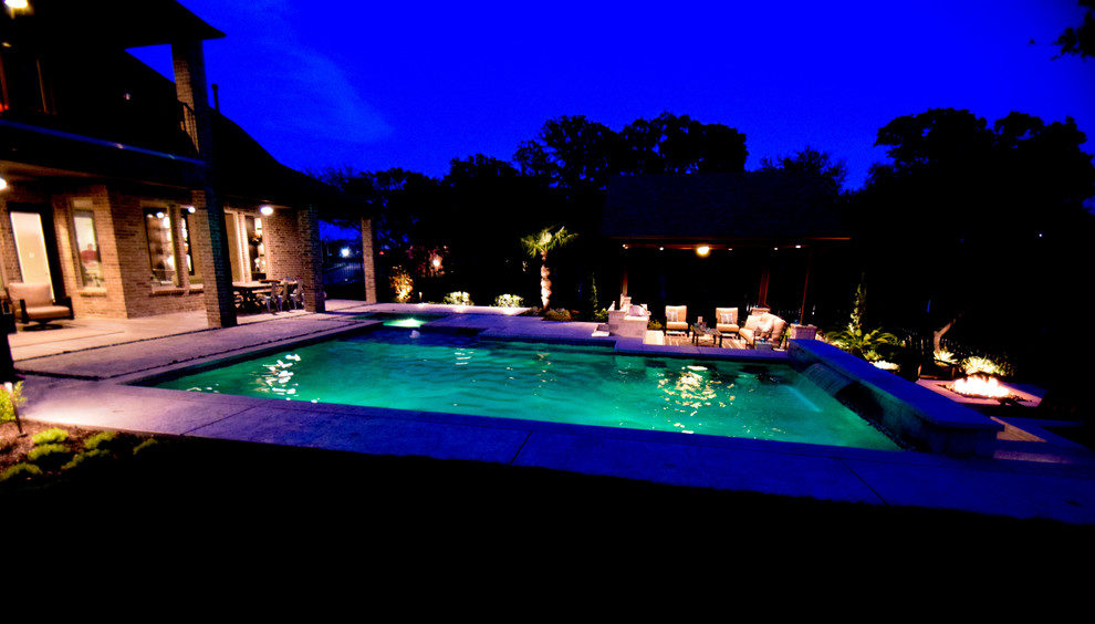 Inspiration for a large contemporary backyard custom-shaped pool in Dallas with a water feature and concrete pavers.