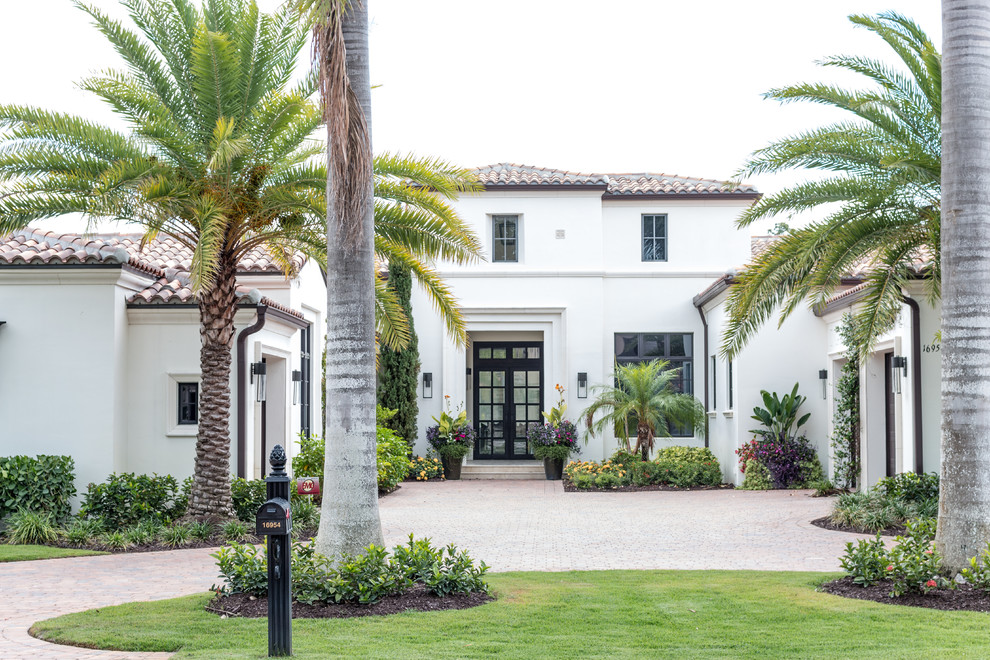 This is an example of a mediterranean two-storey white house exterior in Miami with a tile roof.