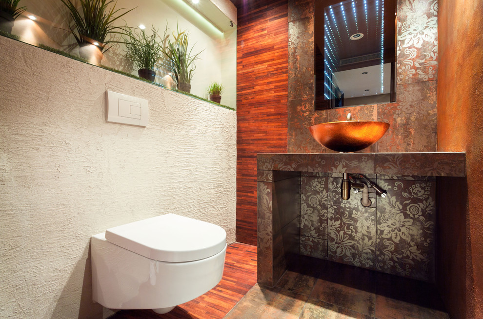 Photo of a mid-sized asian powder room in Atlanta with a wall-mount toilet, multi-coloured tile, porcelain tile, orange walls, porcelain floors, a vessel sink and tile benchtops.