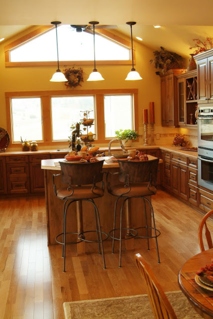 Large mountain style u-shaped medium tone wood floor eat-in kitchen photo with a double-bowl sink, beaded inset cabinets, medium tone wood cabinets, granite countertops, beige backsplash, stainless steel appliances and an island