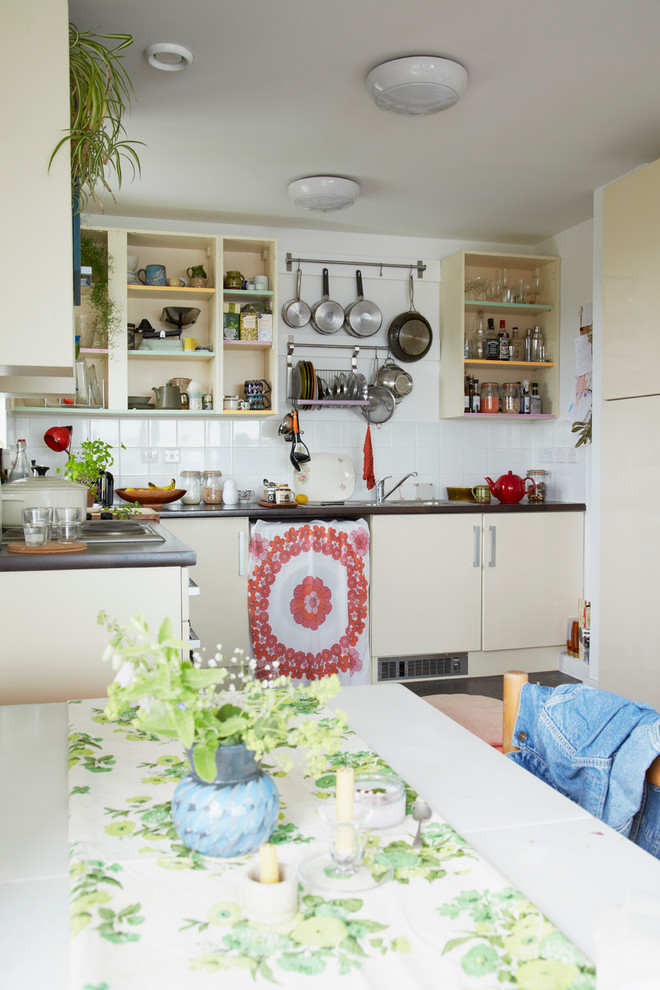 This is an example of a small eclectic l-shaped eat-in kitchen in London with open cabinets, beige cabinets and white splashback.