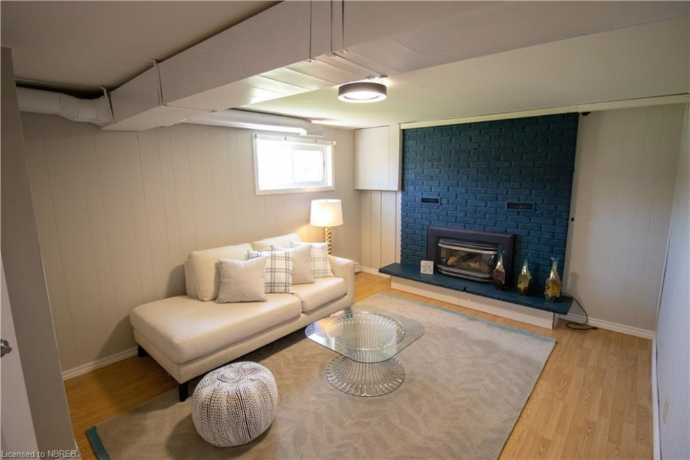 Inspiration pour une petite salle de séjour design fermée avec salle de jeu, un mur gris, sol en stratifié, une cheminée standard, un manteau de cheminée en brique, un téléviseur indépendant et un sol marron.