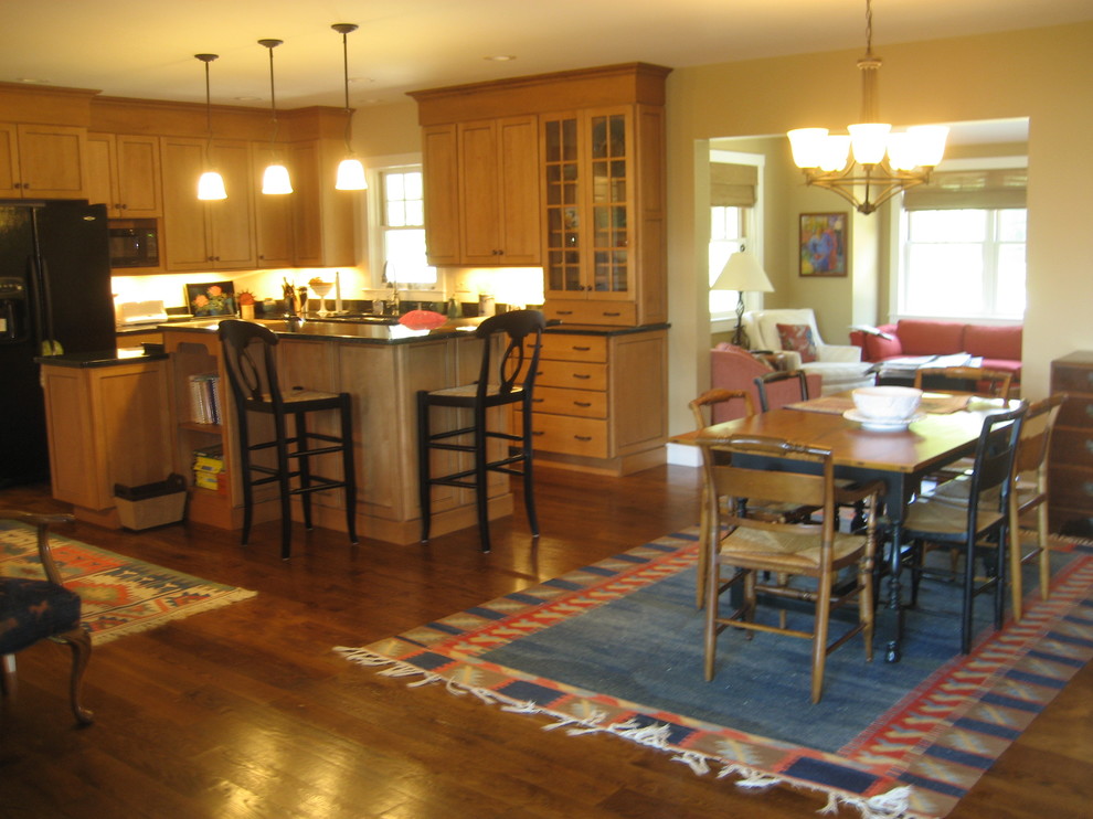 Large mountain style u-shaped medium tone wood floor eat-in kitchen photo in Boston with shaker cabinets, medium tone wood cabinets, solid surface countertops, black appliances and a peninsula