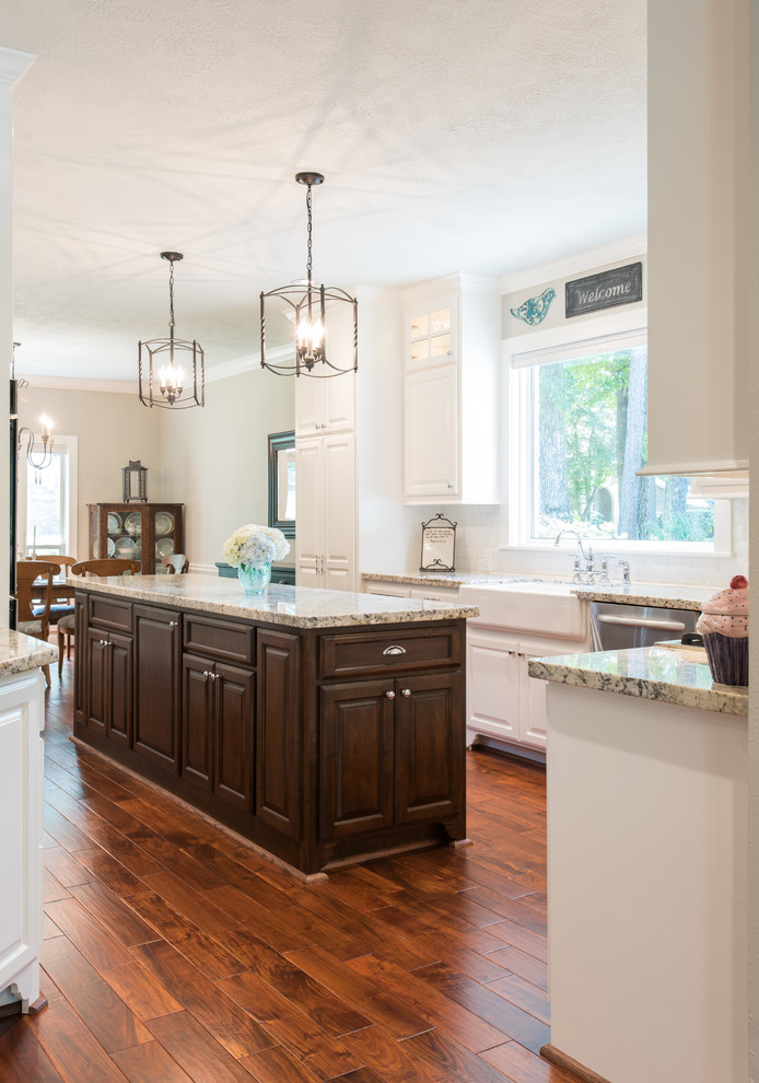 Inspiration for a large transitional u-shaped eat-in kitchen in Houston with a farmhouse sink, raised-panel cabinets, white cabinets, granite benchtops, white splashback, ceramic splashback, stainless steel appliances, medium hardwood floors and with island.