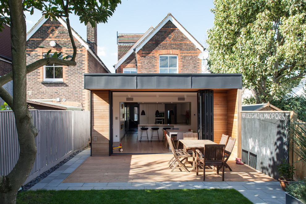 This is an example of a contemporary backyard patio in London with decking and a roof extension.