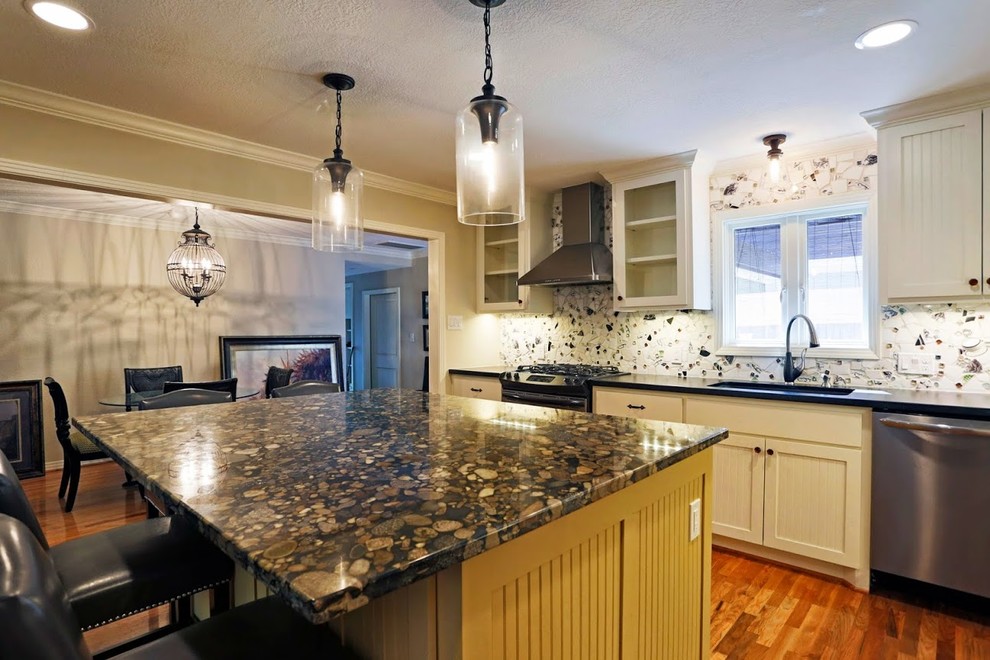 Inspiration for a mid-sized traditional l-shaped eat-in kitchen in Houston with an undermount sink, beaded inset cabinets, light wood cabinets, granite benchtops, beige splashback, stone tile splashback, stainless steel appliances, medium hardwood floors and with island.