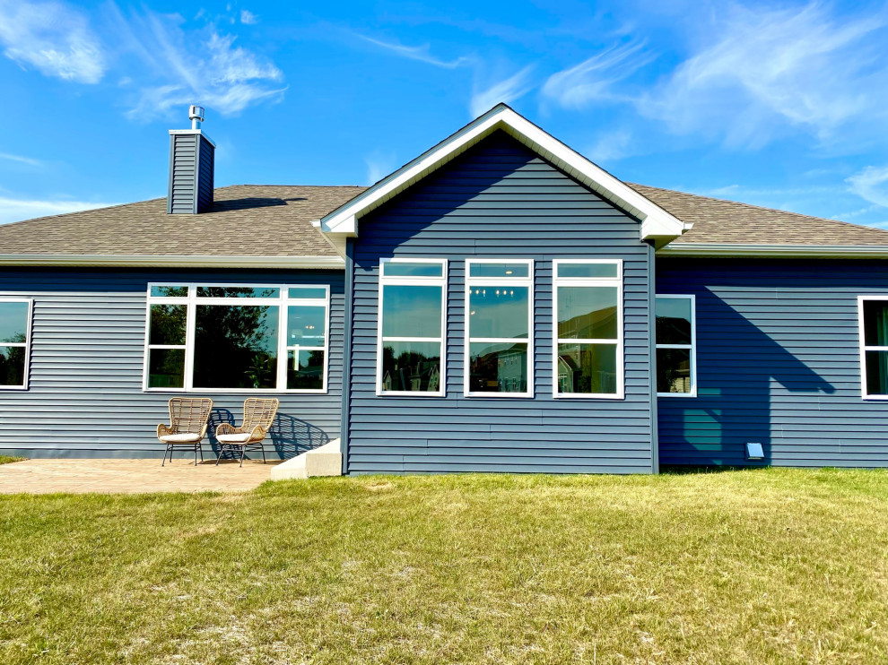 Esempio della villa blu american style a un piano di medie dimensioni con rivestimento in vinile, tetto a padiglione, copertura a scandole, tetto marrone e pannelli sovrapposti