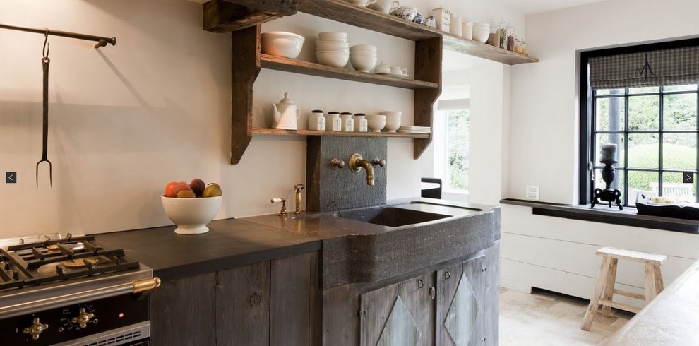 This is an example of a transitional kitchen in New York with a farmhouse sink, open cabinets, distressed cabinets, black appliances, soapstone benchtops, black splashback, stone slab splashback and limestone floors.