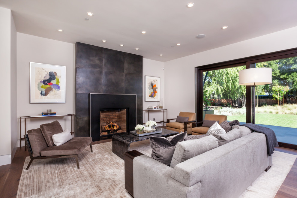 Mid-sized contemporary formal open concept living room in San Francisco with grey walls, medium hardwood floors, a standard fireplace, a metal fireplace surround, no tv and brown floor.