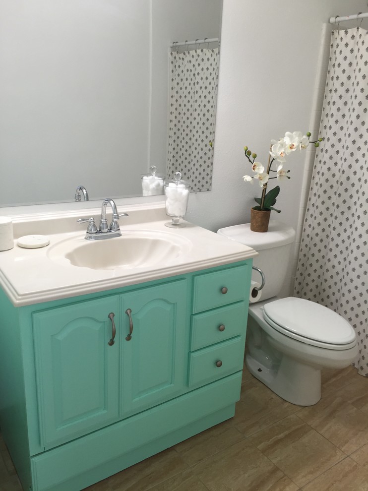 Photo of a small beach style bathroom in Hawaii with turquoise cabinets, a drop-in tub, a shower/bathtub combo, a two-piece toilet, beige tile, ceramic tile, white walls, ceramic floors, an integrated sink and engineered quartz benchtops.
