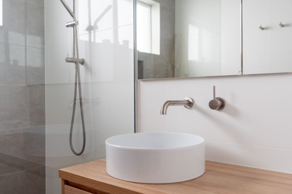 Design ideas for a mid-sized contemporary master bathroom in Wollongong with furniture-like cabinets, light wood cabinets, an open shower, white tile, ceramic tile, ceramic floors, a console sink, multi-coloured floor, a niche, a single vanity and a floating vanity.