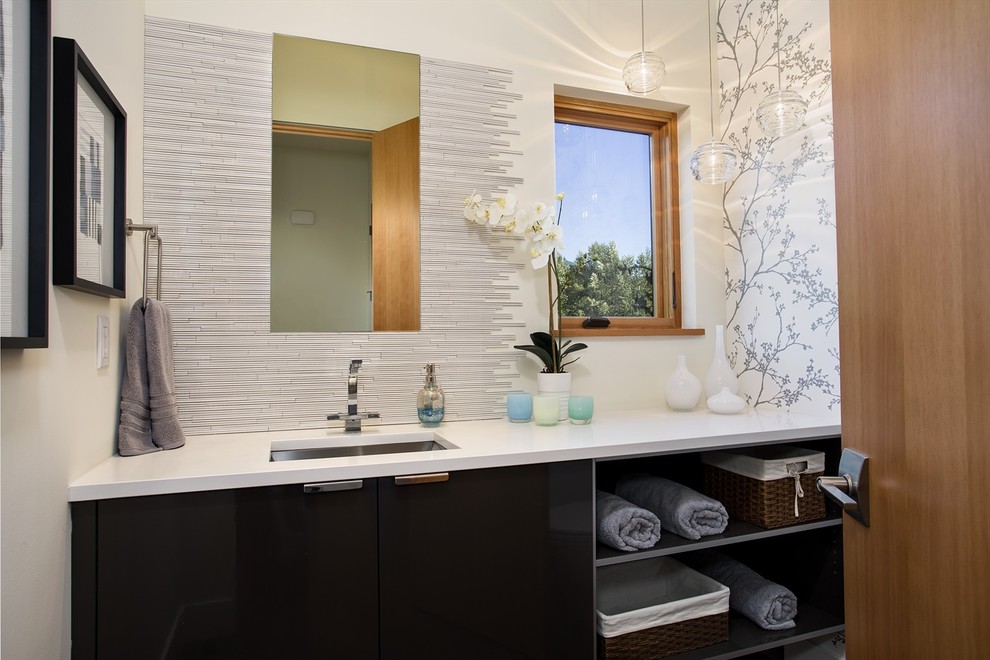 This is an example of a contemporary powder room in Seattle with an undermount sink, flat-panel cabinets, black cabinets, matchstick tile, white tile and white benchtops.