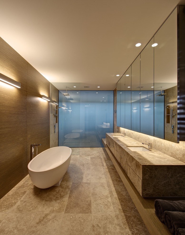 Photo of a large contemporary bathroom in Melbourne with an undermount sink, flat-panel cabinets, marble benchtops, a freestanding tub, stone slab and a curbless shower.