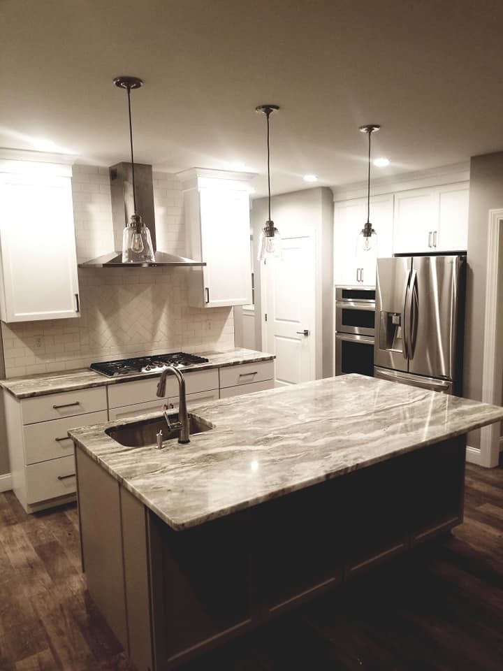 Inspiration for a transitional brown floor kitchen remodel with an undermount sink, flat-panel cabinets, white cabinets, quartzite countertops, white backsplash, subway tile backsplash, stainless steel appliances and an island