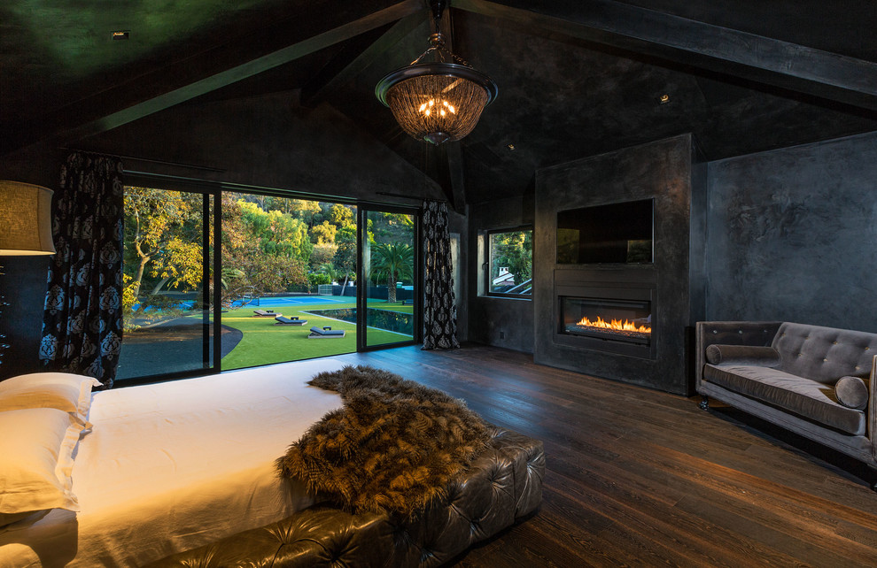 Design ideas for a contemporary master bedroom in Los Angeles with black walls, dark hardwood floors, a ribbon fireplace, a concrete fireplace surround and brown floor.