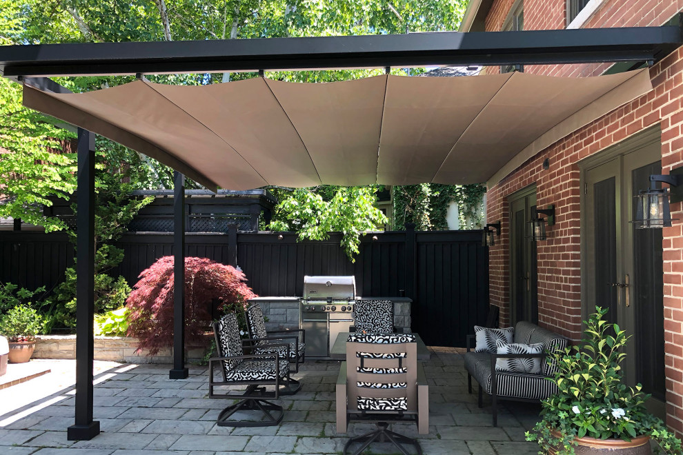 Modern backyard patio in Toronto with concrete pavers and a pergola.