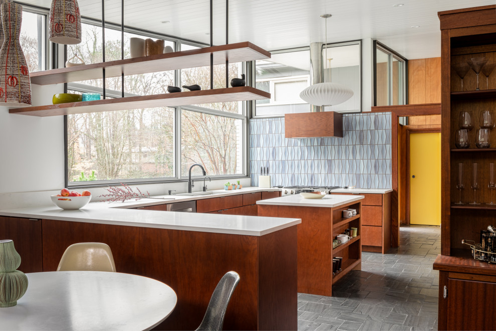 This is an example of a midcentury eat-in kitchen in Atlanta with a drop-in sink, flat-panel cabinets, dark wood cabinets, blue splashback, ceramic splashback, stainless steel appliances, with island, grey floor, white benchtop and slate floors.