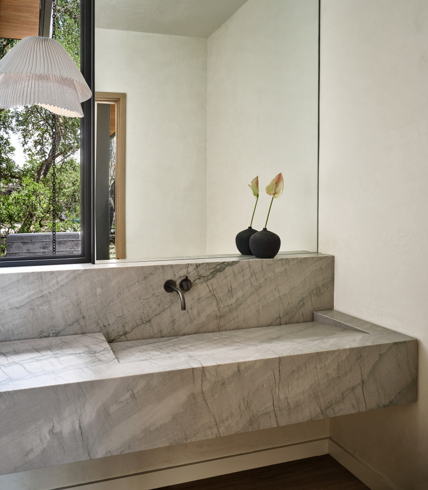 Kleine Moderne Gästetoilette mit weißer Wandfarbe, dunklem Holzboden, integriertem Waschbecken, Marmor-Waschbecken/Waschtisch, grauer Waschtischplatte und schwebendem Waschtisch in Austin