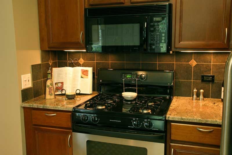 Transitional u-shaped medium tone wood floor kitchen pantry photo in Chicago with raised-panel cabinets, medium tone wood cabinets and granite countertops