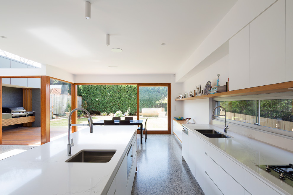 Inspiration for a large contemporary l-shaped open plan kitchen in Sydney with a double-bowl sink, flat-panel cabinets, white cabinets, solid surface benchtops, stainless steel appliances, concrete floors and with island.