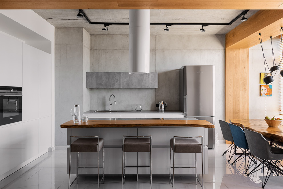 This is an example of an industrial open plan kitchen in Yekaterinburg with flat-panel cabinets, grey cabinets, grey splashback, black appliances, with island and white floor.
