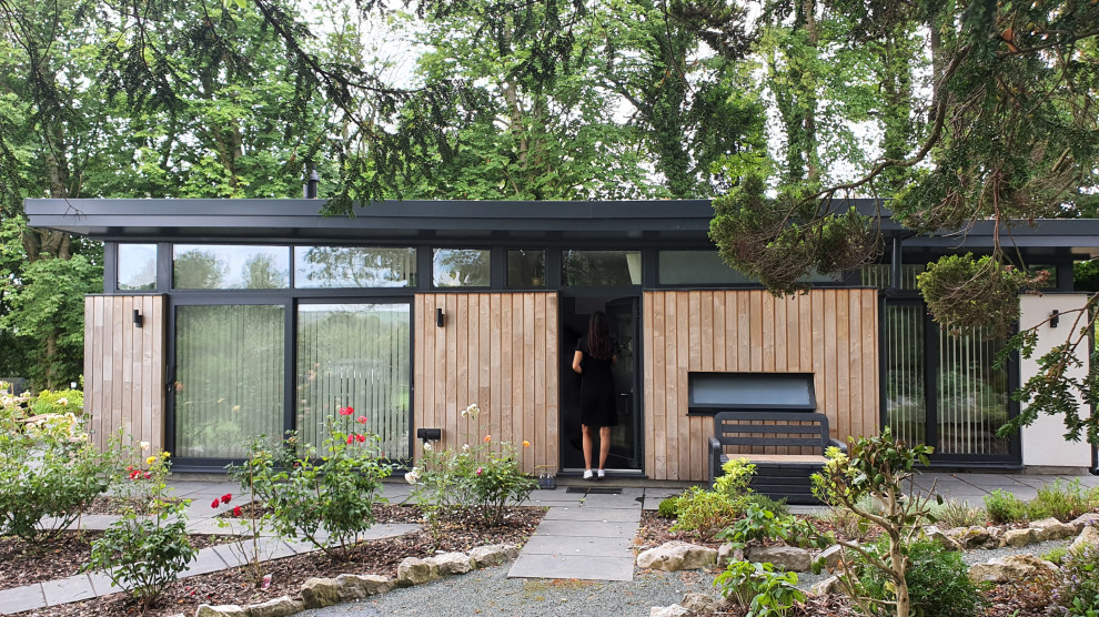 На фото: маленький, одноэтажный, деревянный мини дом в современном стиле с плоской крышей, зеленой крышей и отделкой доской с нащельником для на участке и в саду с