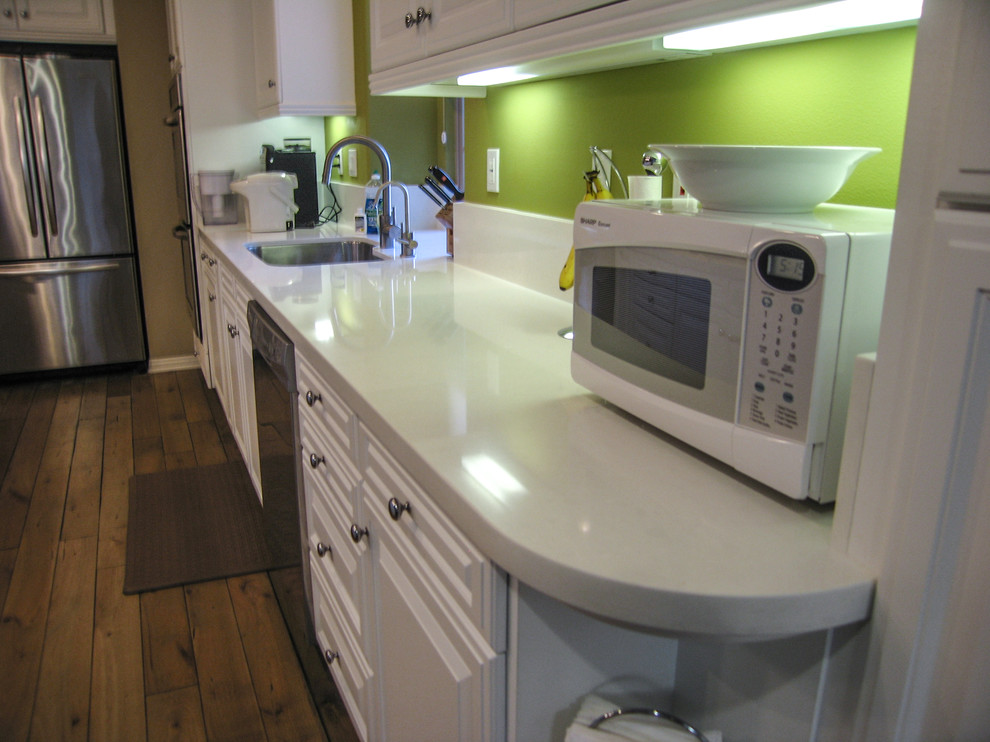 Example of a mid-sized trendy galley light wood floor open concept kitchen design in Orange County with an undermount sink, raised-panel cabinets, white cabinets, quartzite countertops, green backsplash, stone slab backsplash, stainless steel appliances and an island