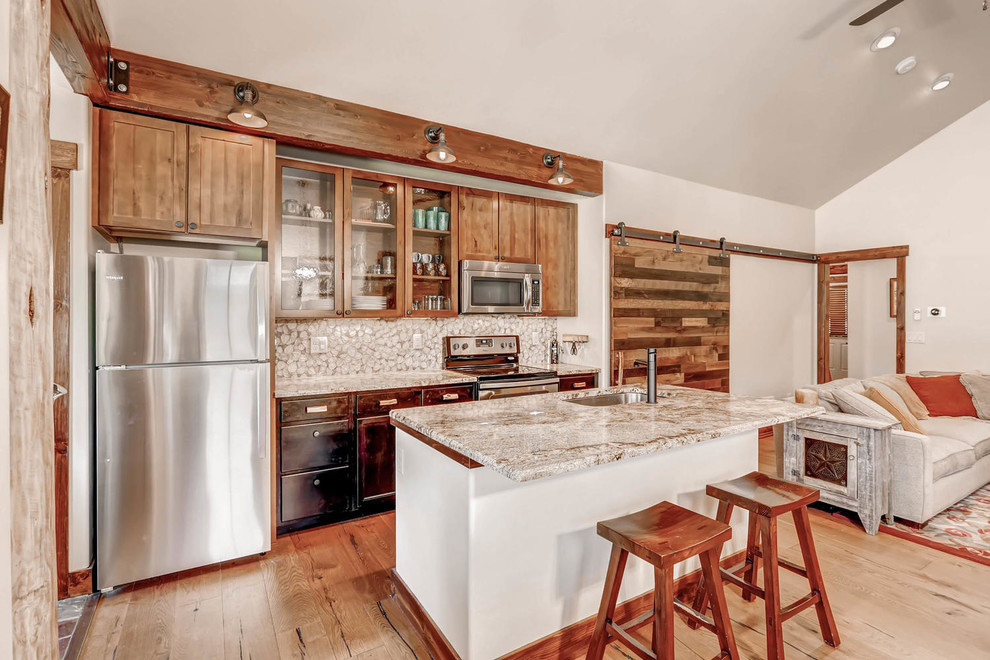 Small arts and crafts open plan kitchen in Denver with a single-bowl sink, shaker cabinets, black cabinets, granite benchtops, white splashback, porcelain splashback, stainless steel appliances, medium hardwood floors and with island.