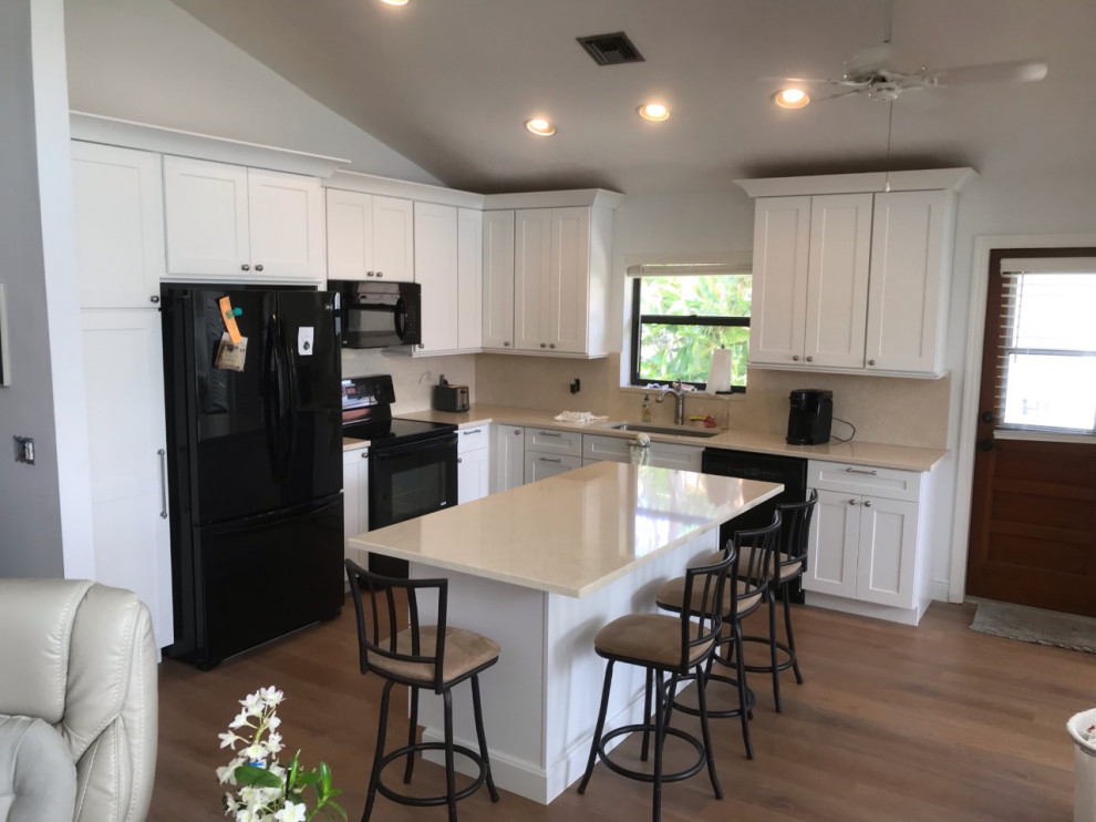 Inspiration for a transitional vinyl floor and brown floor eat-in kitchen remodel with shaker cabinets, white cabinets, quartz countertops, quartz backsplash, an island, a single-bowl sink, beige backsplash, black appliances and beige countertops
