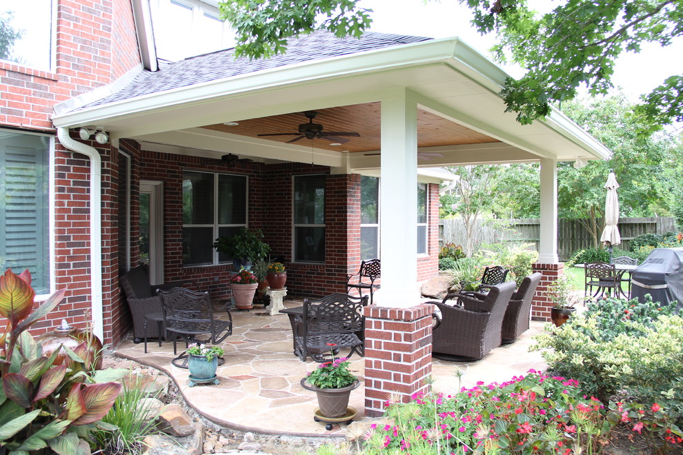Mid-sized traditional backyard patio in Houston with stamped concrete and a roof extension.