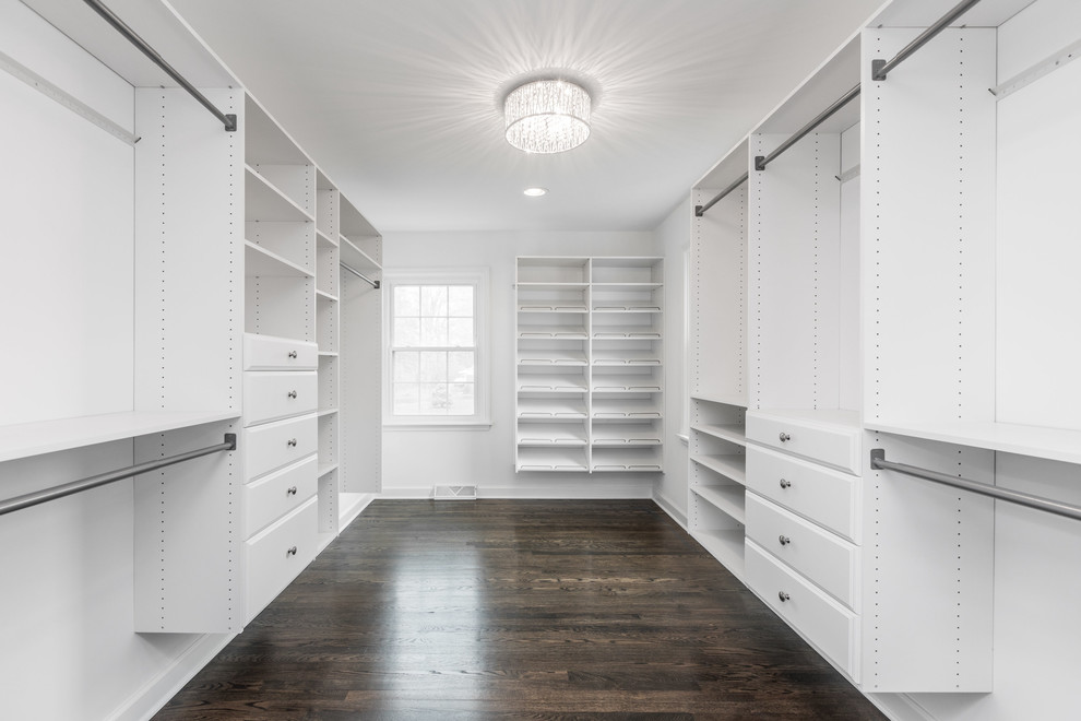 Photo of a traditional gender-neutral walk-in wardrobe in Indianapolis with white cabinets, dark hardwood floors and brown floor.